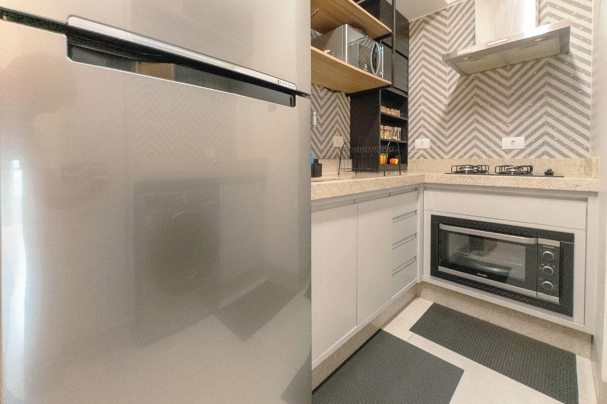 A kitchen with a built-in oven, a microwave, and a stainless steel refrigerator.