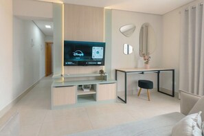 Een moderne woonkamer met een flatscreen televisie, een bureau met stoel, een spiegel en een bed.