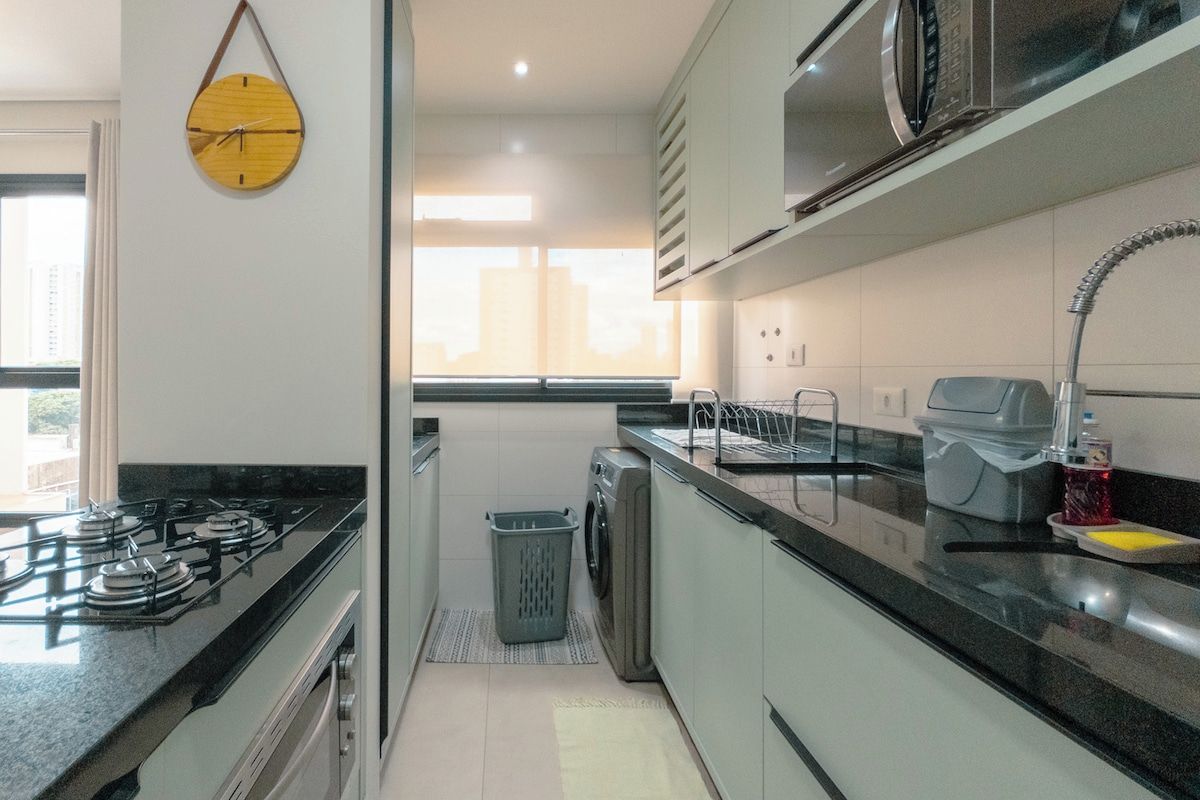 A compact kitchen with a gas stove, microwave, and sink.