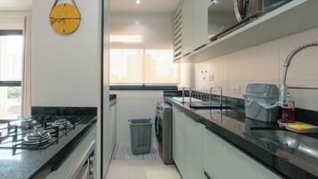 A compact kitchen with a gas stove, microwave, and sink.