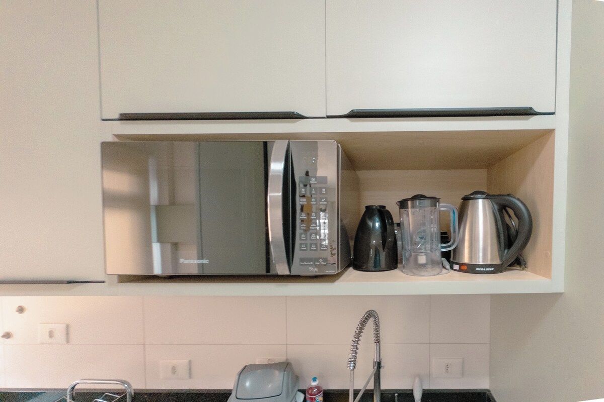 Cozinha equipada com micro-ondas, chaleira e máquina de café.