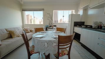 Un espace repas avec une table ronde, des chaises et une vue sur la ville grâce à de grandes fenêtres.
