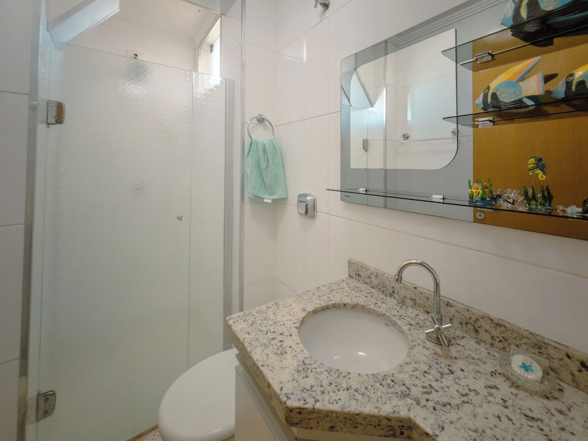 Une salle de bain avec un lavabo en granit, une douche en verre et des toilettes blanches.