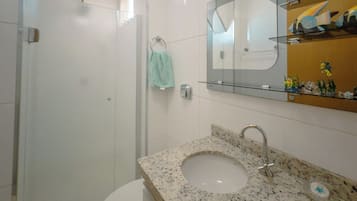 Une salle de bain avec un lavabo en granit, une douche en verre et des toilettes blanches.