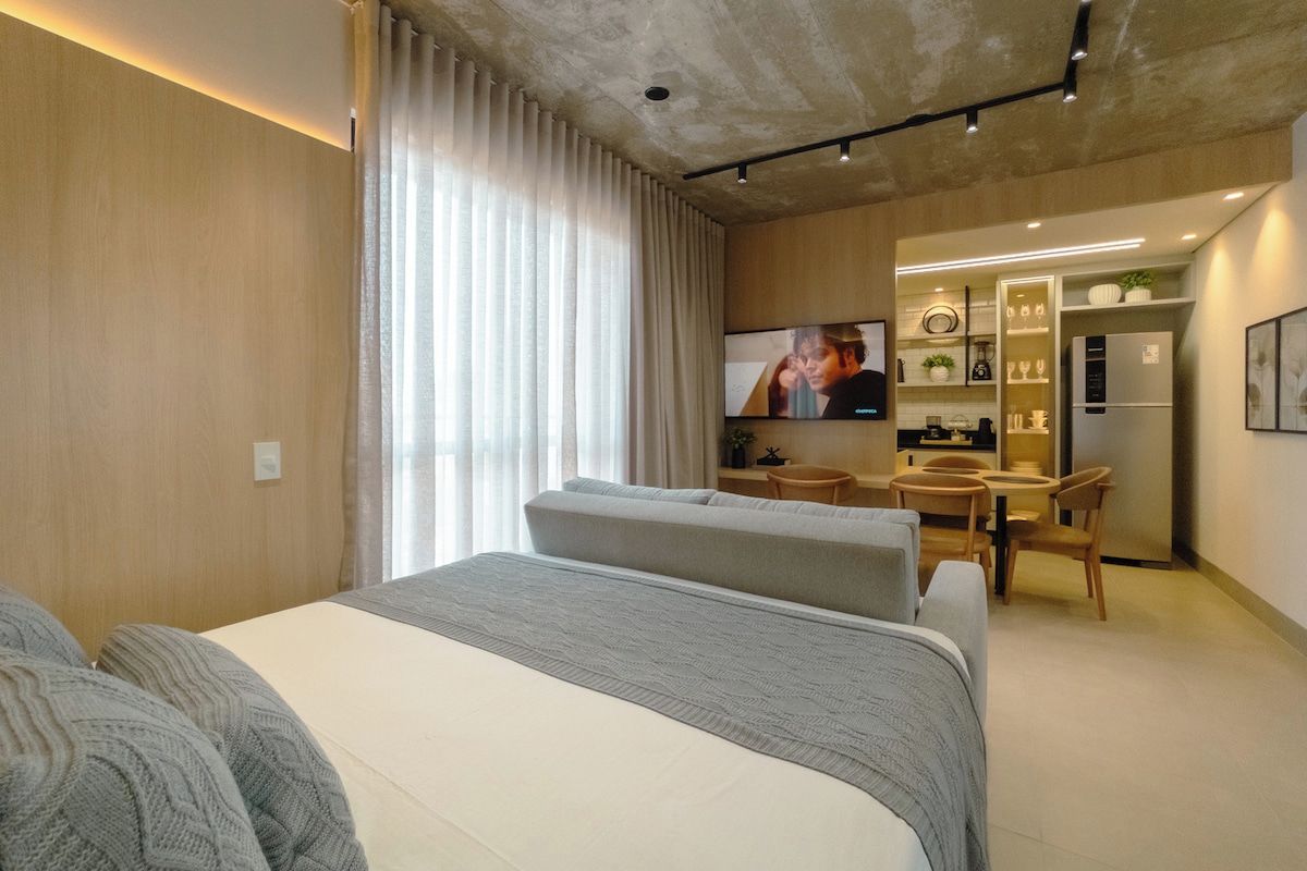 A modern hotel room with a large bed, a desk, and a television.