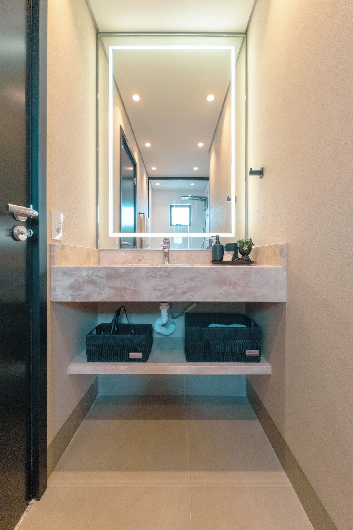 A modern bathroom with a large mirror, a sink, and storage shelves.