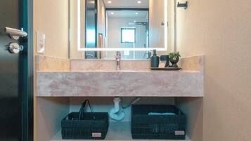 A modern bathroom with a large mirror, a sink, and storage shelves.