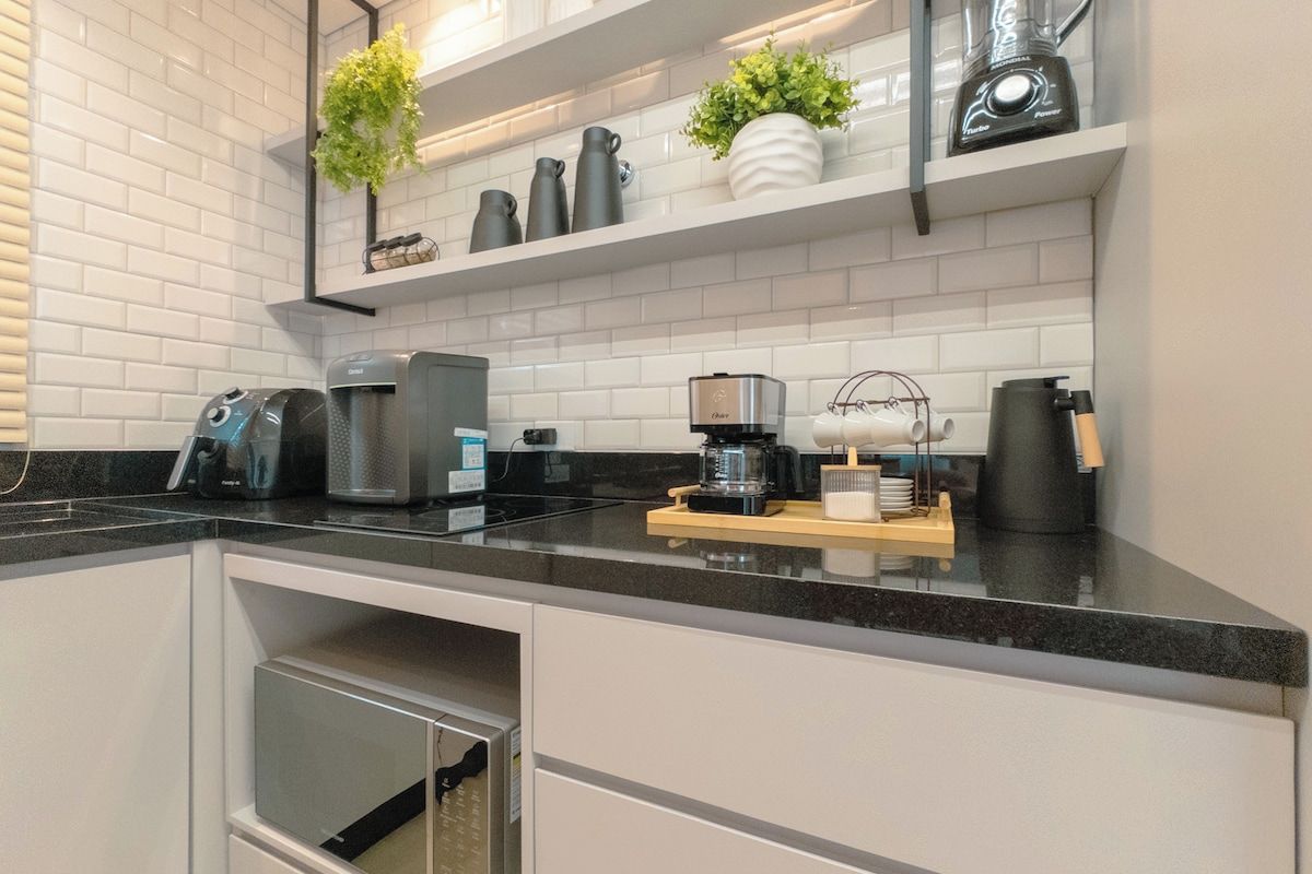 A modern kitchen with white subway tiles, black countertops, and stainless steel appliances.