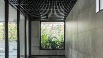 A modern indoor swimming pool with a grid-patterned ceiling, large windows, and a view of greenery outside.