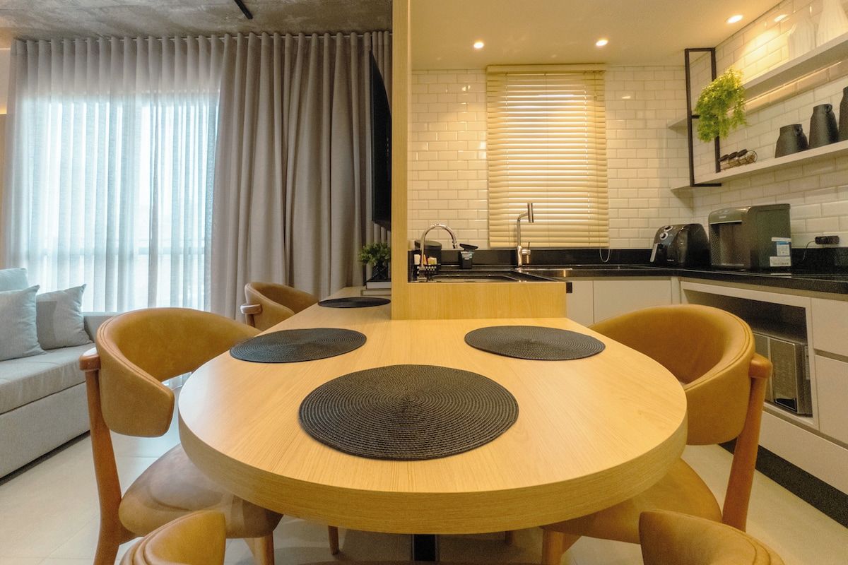 A modern kitchen with a round dining table, chairs, and a built-in oven.