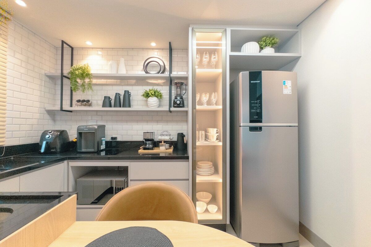 A compact kitchen with a built-in refrigerator, a coffee maker, and a sink.