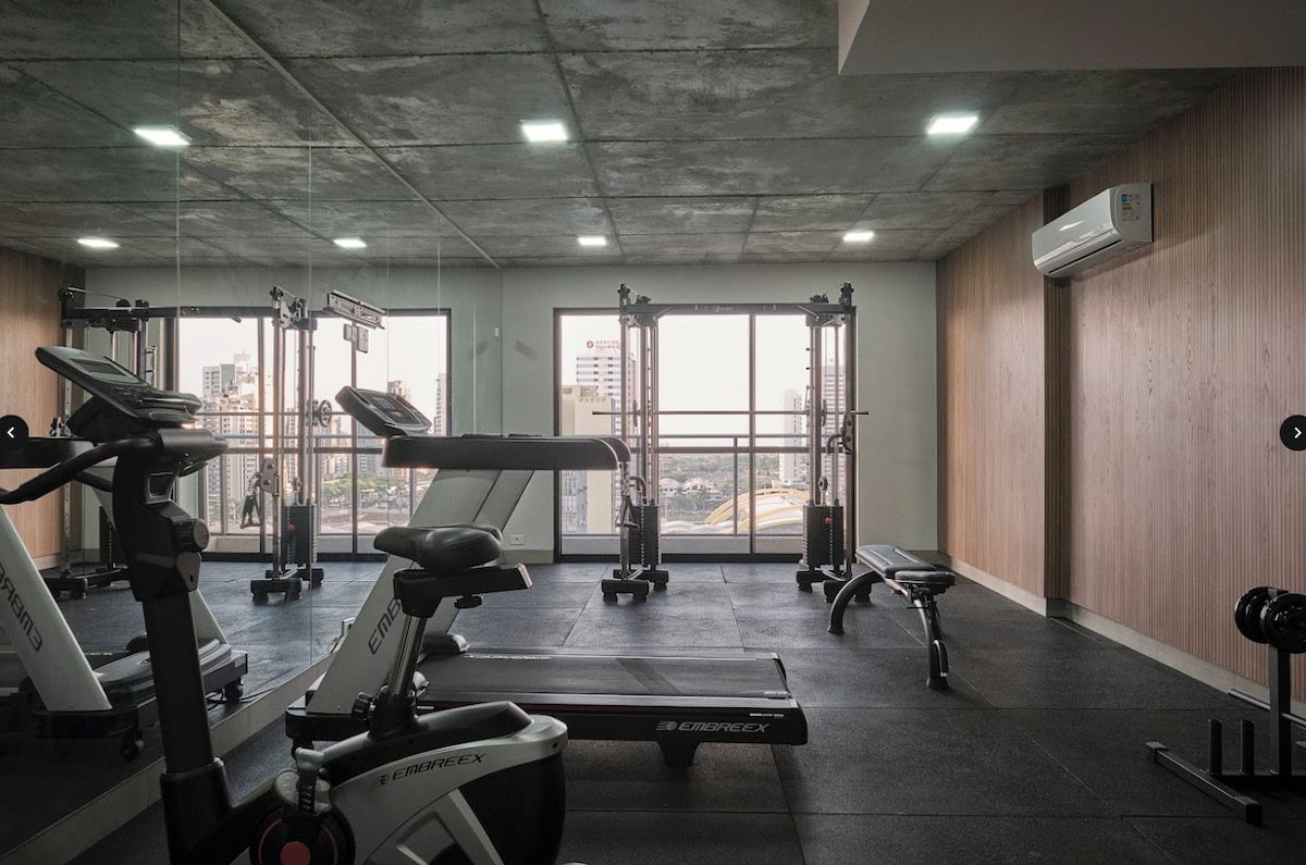 Un gimnasio con máquinas de cardio, equipo de levantamiento de pesas y amplias ventanas con vista a la ciudad.