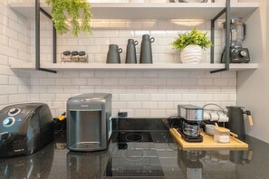 Een keuken met een koffiezetapparaat, broodrooster en blender op het aanrecht.