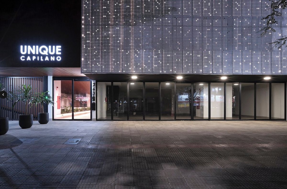 A modern building with a large illuminated sign reading 'UNIQUE CAPILANO' and a spacious entrance area.