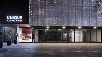 A modern building with a large illuminated sign reading 'UNIQUE CAPILANO' and a spacious entrance area.