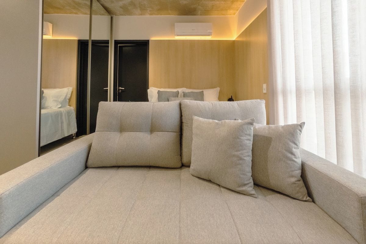 A modern hotel room with a large bed, a mirror, and a view of the outdoors.