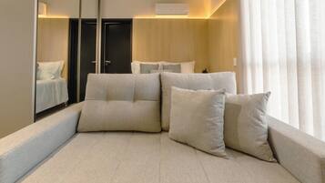 A modern hotel room with a large bed, a mirror, and a view of the outdoors.