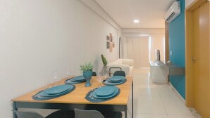 A dining area with a wooden table set for four, chairs, a vase with a plant, and a wall-mounted air conditioner. - Top Location in the Heart of Maringa - JR509 (Maringá)