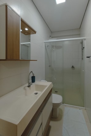 Ein Badezimmer mit Waschbecken, Spiegel, Toilette und Duschkabine.