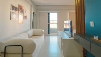A modern hotel room with a sofa, a desk, and a refrigerator.