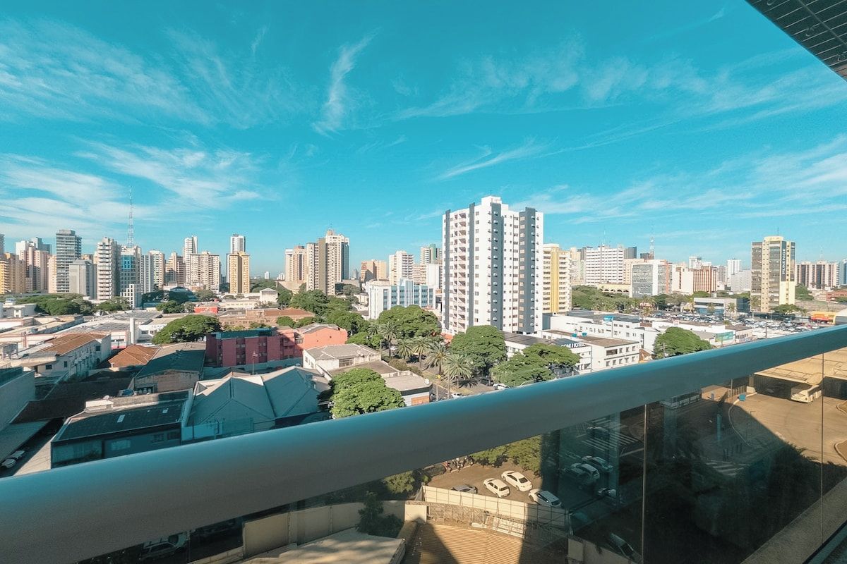 A cityscape with high-rise buildings, a clear sky, and a view from a balcony.