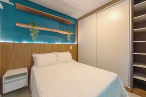 Ein Schlafzimmer mit Bett, Nachttisch, Kleiderschrank und einem Regal mit Pflanzen.