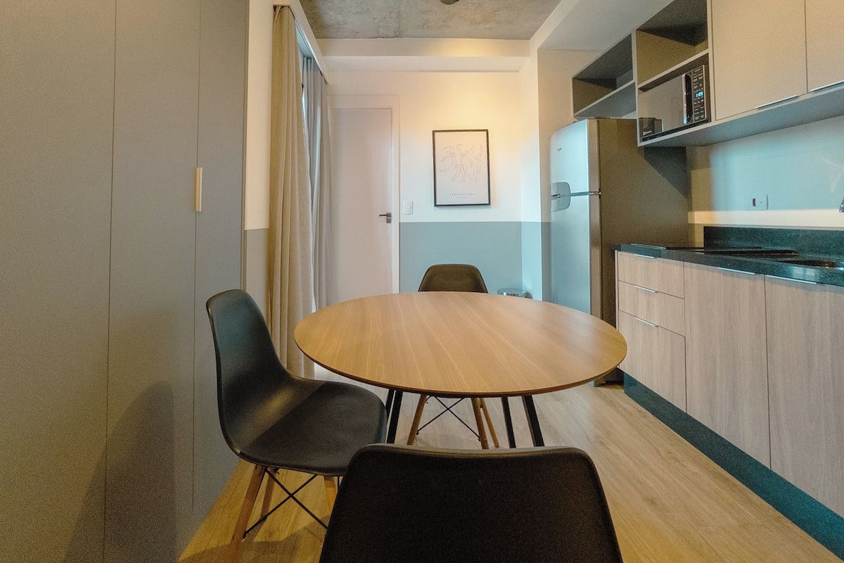 A compact kitchen with a dining table and chairs, a microwave, and cabinets.