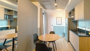 Cozinha moderna com eletrodomésticos embutidos, área de refeições com mesa e cadeiras redondas e vista para o espaço de estar adjacente.
