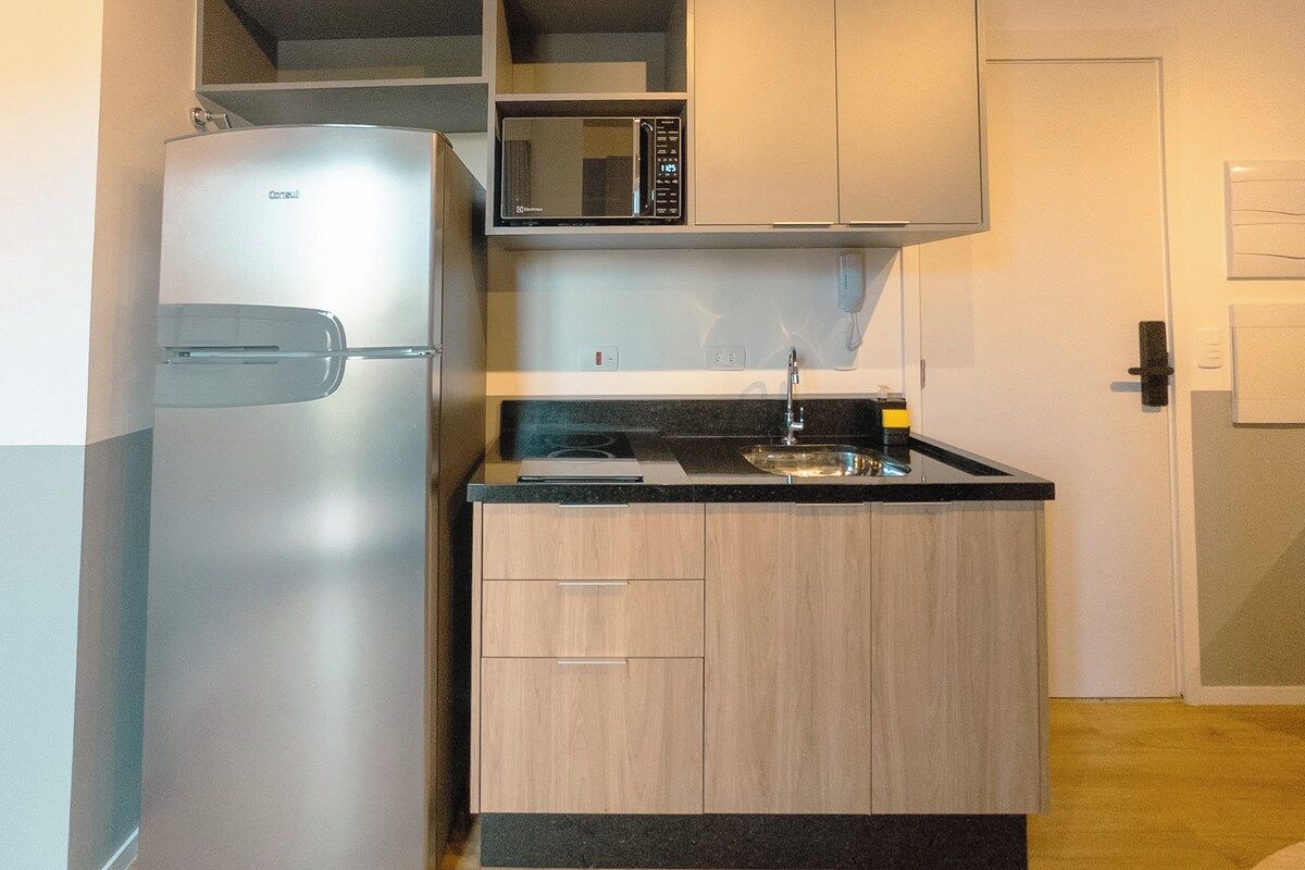 A compact kitchen with a refrigerator, microwave, and sink.