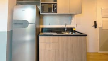 A compact kitchen with a refrigerator, microwave, and sink.