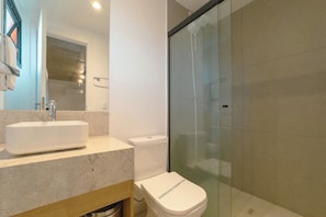 Een moderne badkamer met een wit wastafelmeubel, toilet en een douchecabine van glas.