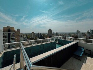 Ein Dachpool mit Blick auf die Stadt, umgeben von Gebäuden und blauem Himmel.