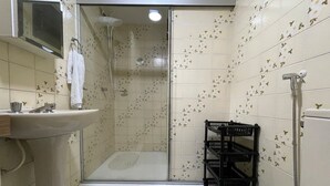 Casa de banho com cabine de chuveiro de vidro, lavatório e sanita.