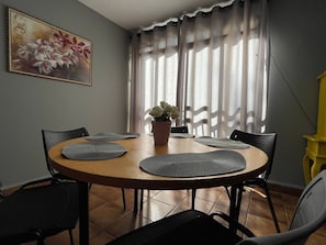 Een eetgedeelte met een ronde tafel, zwarte stoelen en een potplant.