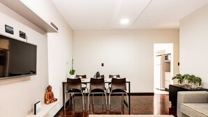 Ein modernes Wohnzimmer mit einem Flachbildfernseher, einem Essbereich mit Tisch und Stühlen sowie einer Couch.