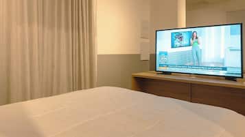 Una habitación de hotel con una cama, un televisor sobre un mueble de madera y una cortina.