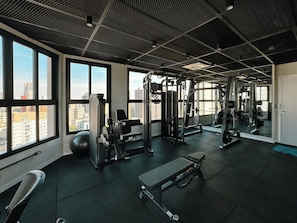 A gym with various exercise equipment, large windows, and a view of the city.