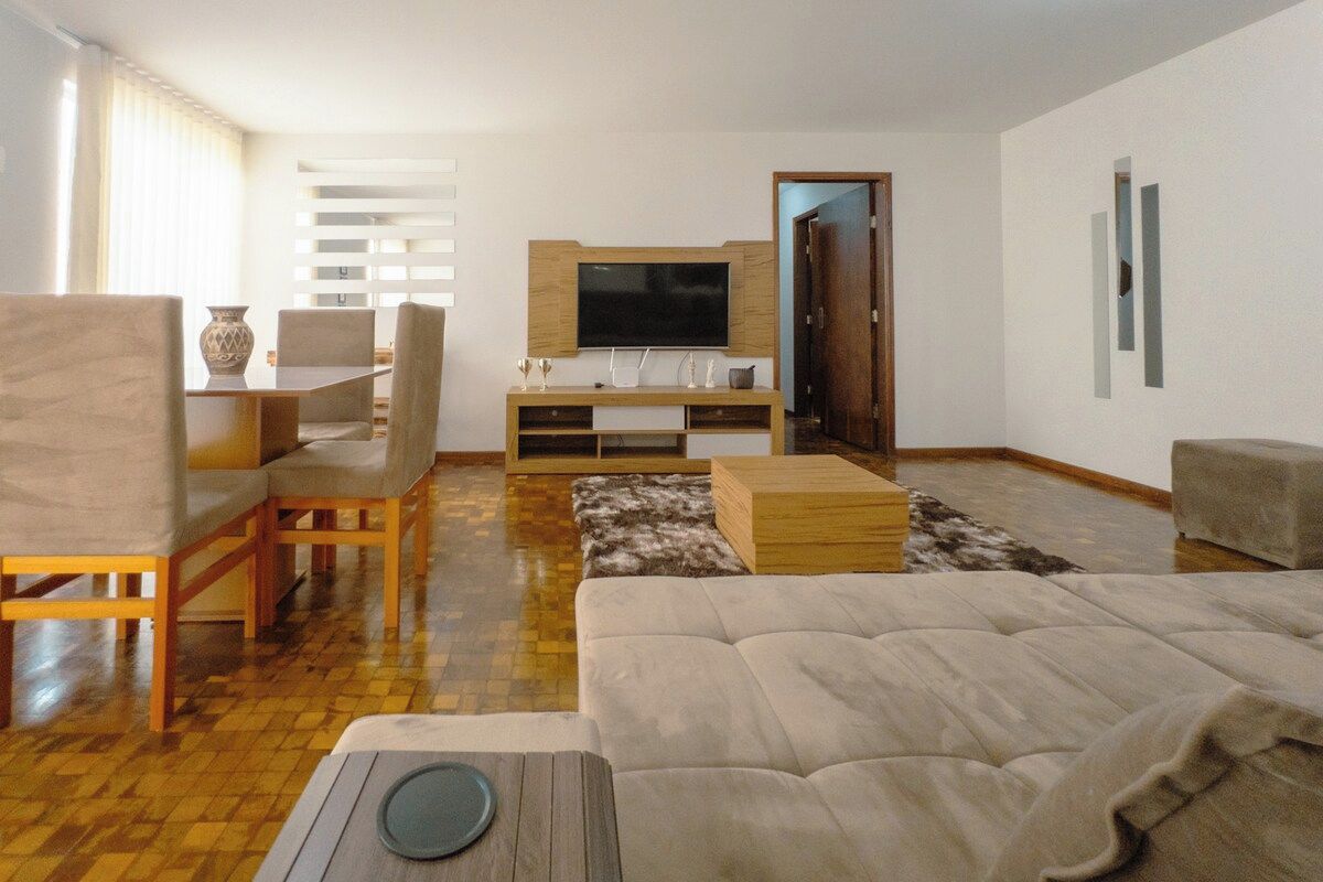 Ein Wohnzimmer mit einer Couch, einem Couchtisch, einem Fernseher und einem Essbereich mit Stühlen und einem Tisch.