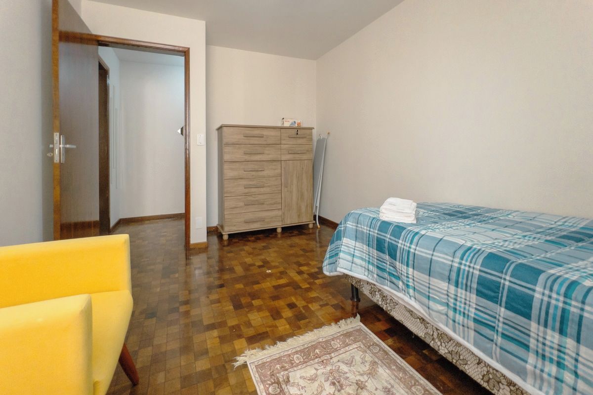 A bedroom with a bed, a dresser, a chair, and a door.