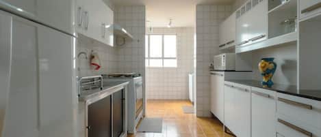 A kitchen with white cabinets, a microwave, and a window providing natural light.