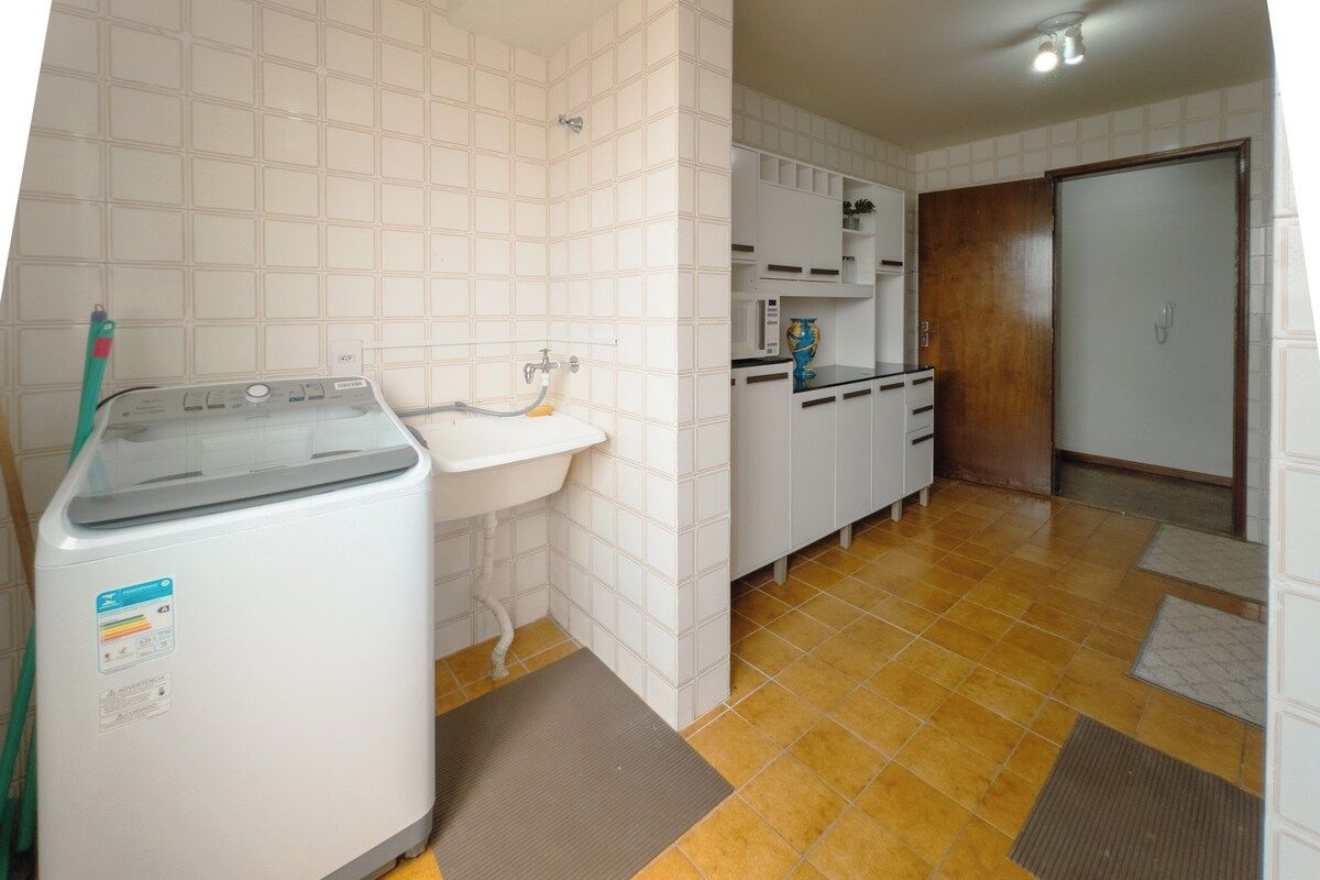 A compact kitchen with a washing machine, a sink, and cabinets.