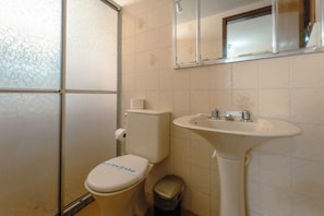 Een badkamer met toilet, wastafel en spiegel.