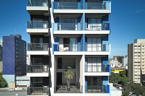 A multi-story building with balconies, large windows, and a potted plant on the ground floor. - Your Ideal Apartment in Downtown Maringa - CA1306 (Maringá)