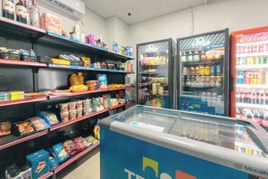 L'intérieur d'une épicerie, avec des étagères remplies de divers produits alimentaires et deux distributeurs réfrigérés de boissons.