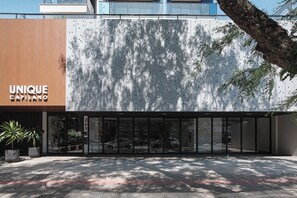 Une façade de bâtiment moderne dotée d’un design unique de panneaux perforés, d’une entrée bien visible et d’une vue dégagée sur la rue.