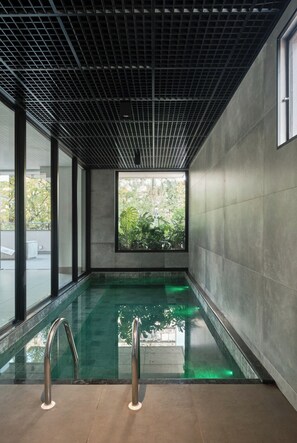 A modern indoor swimming pool with a grid-patterned ceiling and large windows. - Your Ideal Apartment in Downtown Maringa - CA1306 (Maringá)