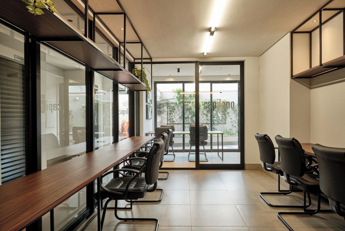A modern conference room with a long table and chairs, large windows, and a view of the outside.