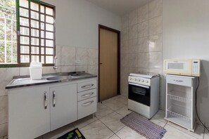A kitchen with a sink, cabinets, a stove, and a microwave. - Budget Apartment near Unicesumar - GI08 (Maringá)