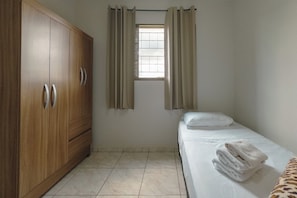 A room with a bed, a wardrobe, and a window with curtains. - Budget Apartment near Unicesumar - GI08 (Maringá)