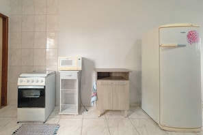 A kitchen with a white oven, microwave, and refrigerator, a wooden cabinet, and a tiled floor. - Budget Apartment near Unicesumar - GI08 (Maringá)